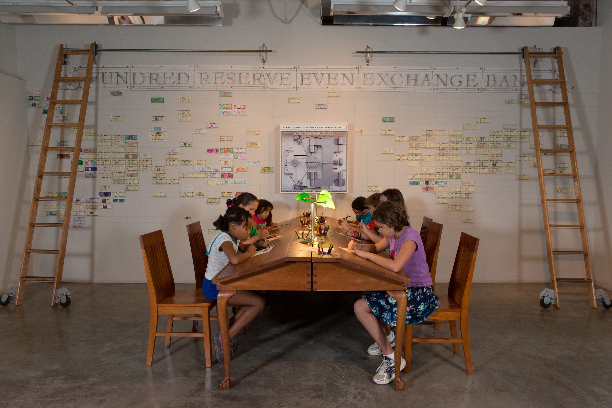 Students sitting at a table draw Fundreds in the Fundred Reserve Even Exchange Bank. 