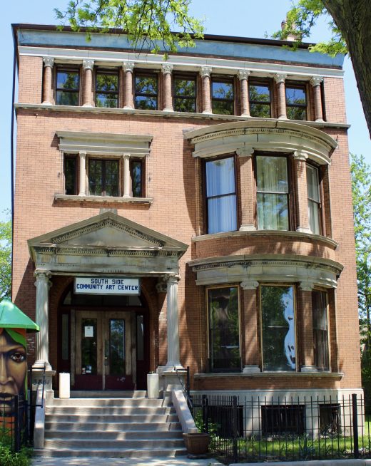 A three story brick house with Greek revival casements and doorway.