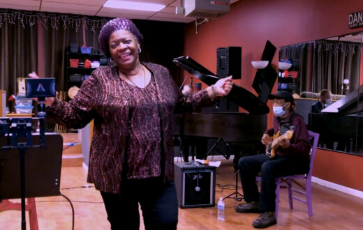 A music studio with a jazz musician singing in front of a bass player and pianist