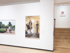 Gallery view with two large scale photographs of monuments and a small drawing up a flight of stairs