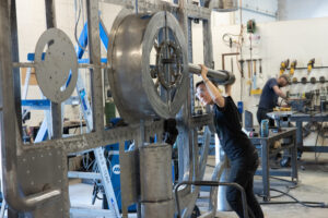 A person hoists a metal rod during the fabrication process of a bank vault