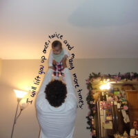 A person lifts a baby into the air, surrounded by the hand-written message: I will lift you up, once, twice, and many more times
