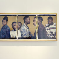 Gallery installation featuring a three-panel photograph of students.