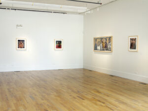 Gallery installation displaying four photographs, each a portrait of a student.
