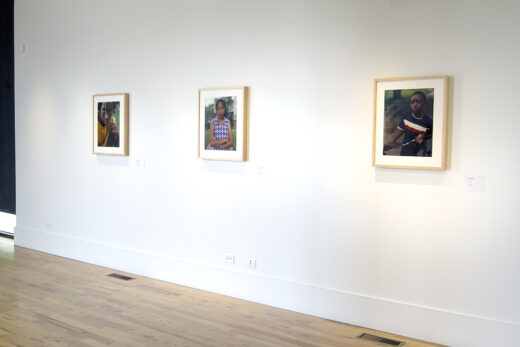 Gallery installation displaying three photographs, each a portrait of a student.