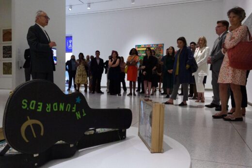 Mel Chin speaks to a group of people during a gallery tour.