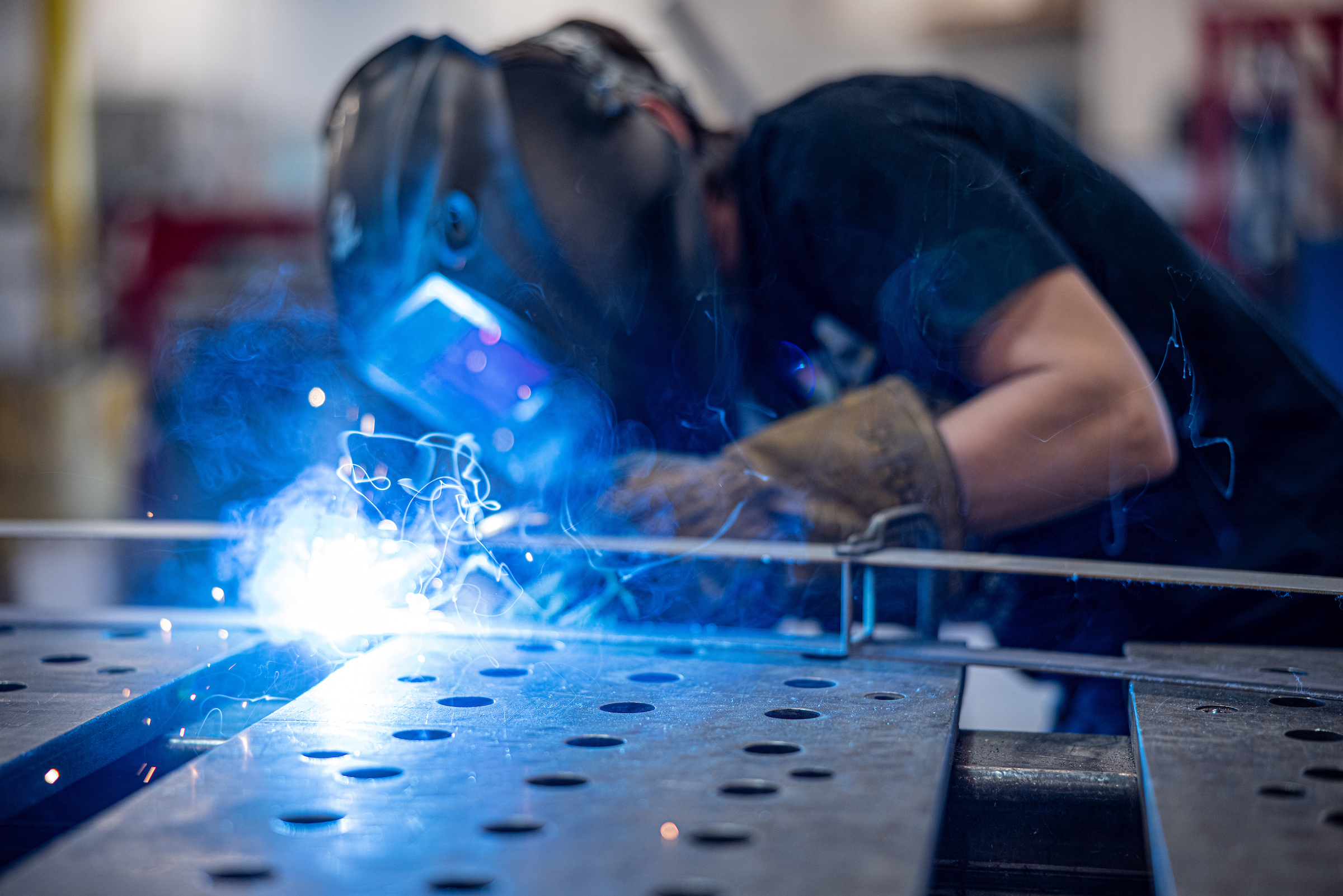 A worker uses a torch to work on a piece of metal