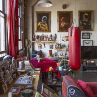 An apartment filled with paintings, personal items, figurines, a punching bag, and ephemera.