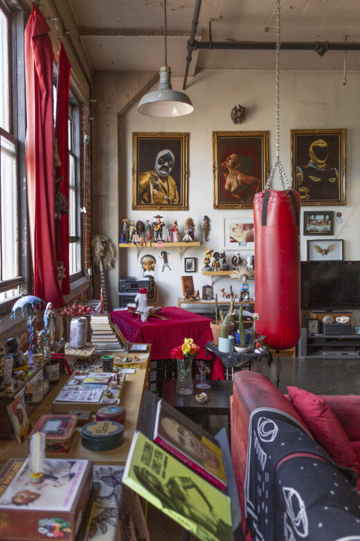 An apartment filled with paintings, personal items, figurines, a punching bag, and ephemera.