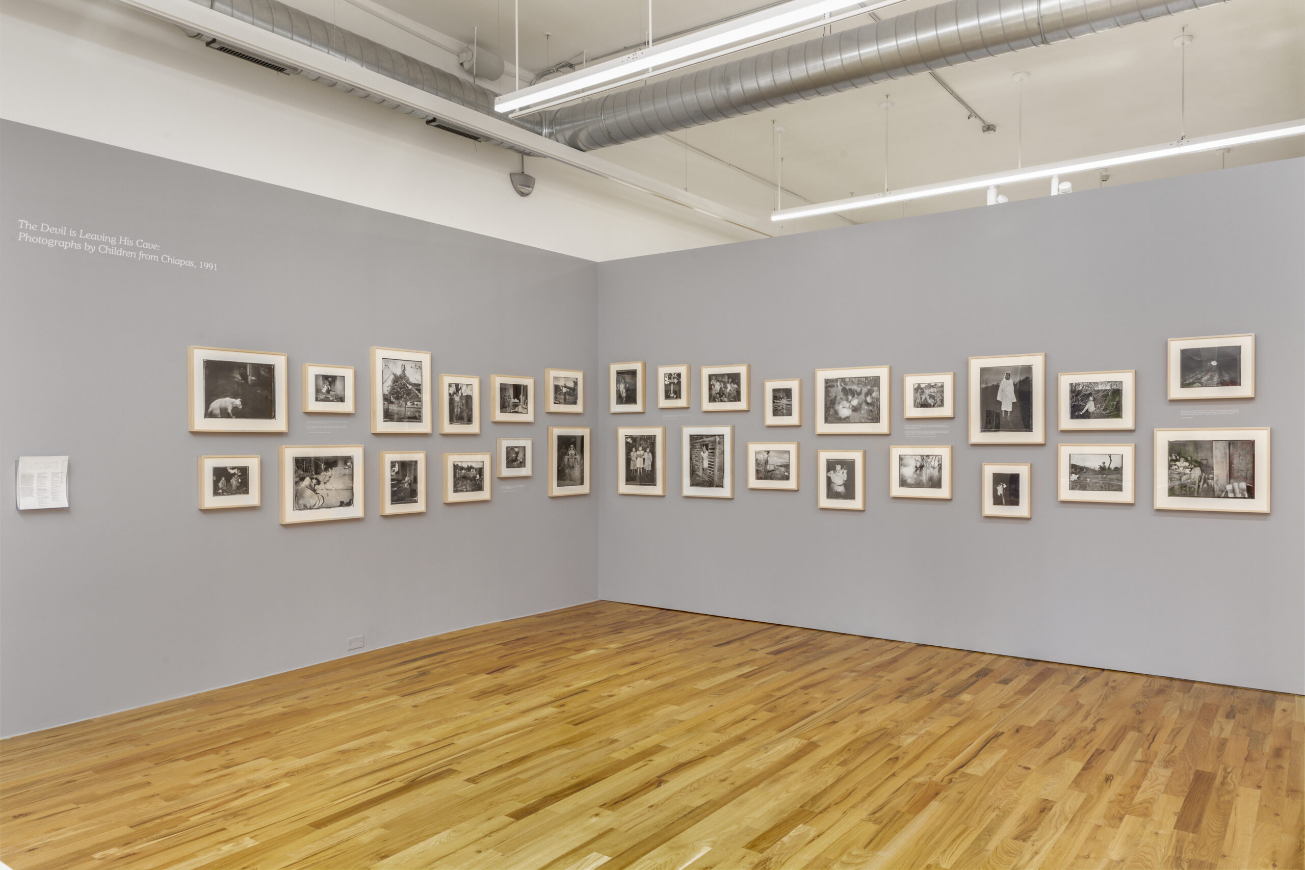 A series of black and white photographs set against a grey wall.