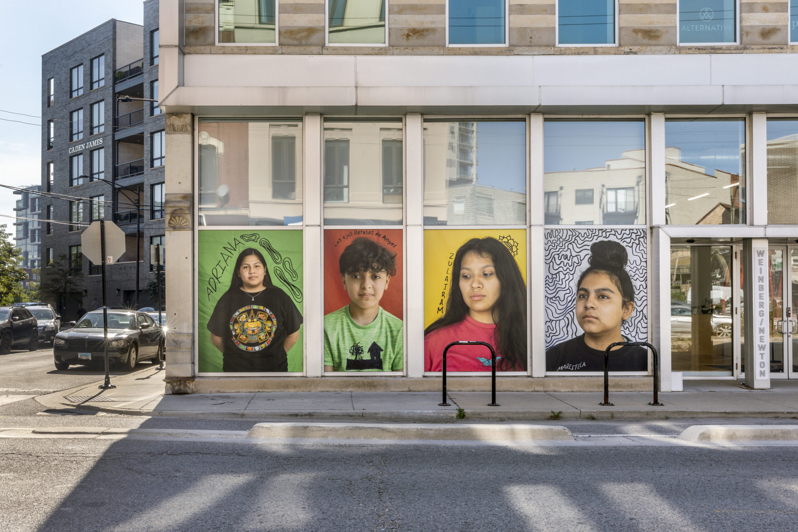 Street level of the gallery featuring large scale window coverings of student portraits.