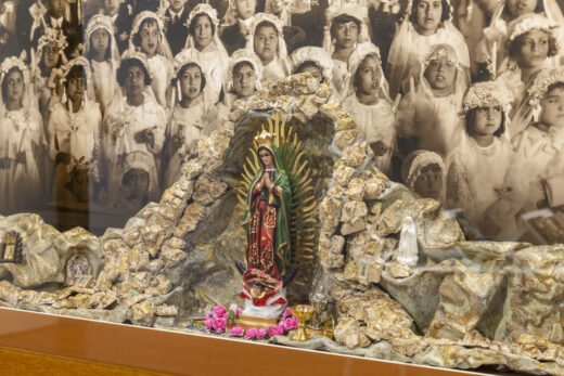 A shadow box altar with a photographic backdrop of girls at a religious ceremony