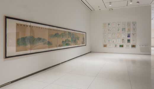 Gallery installation with framed children's drawings and a long scroll landscape painting.
