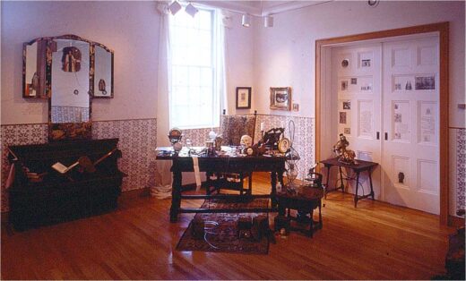 Globes, skulls, and other material sit on a large wooden desk